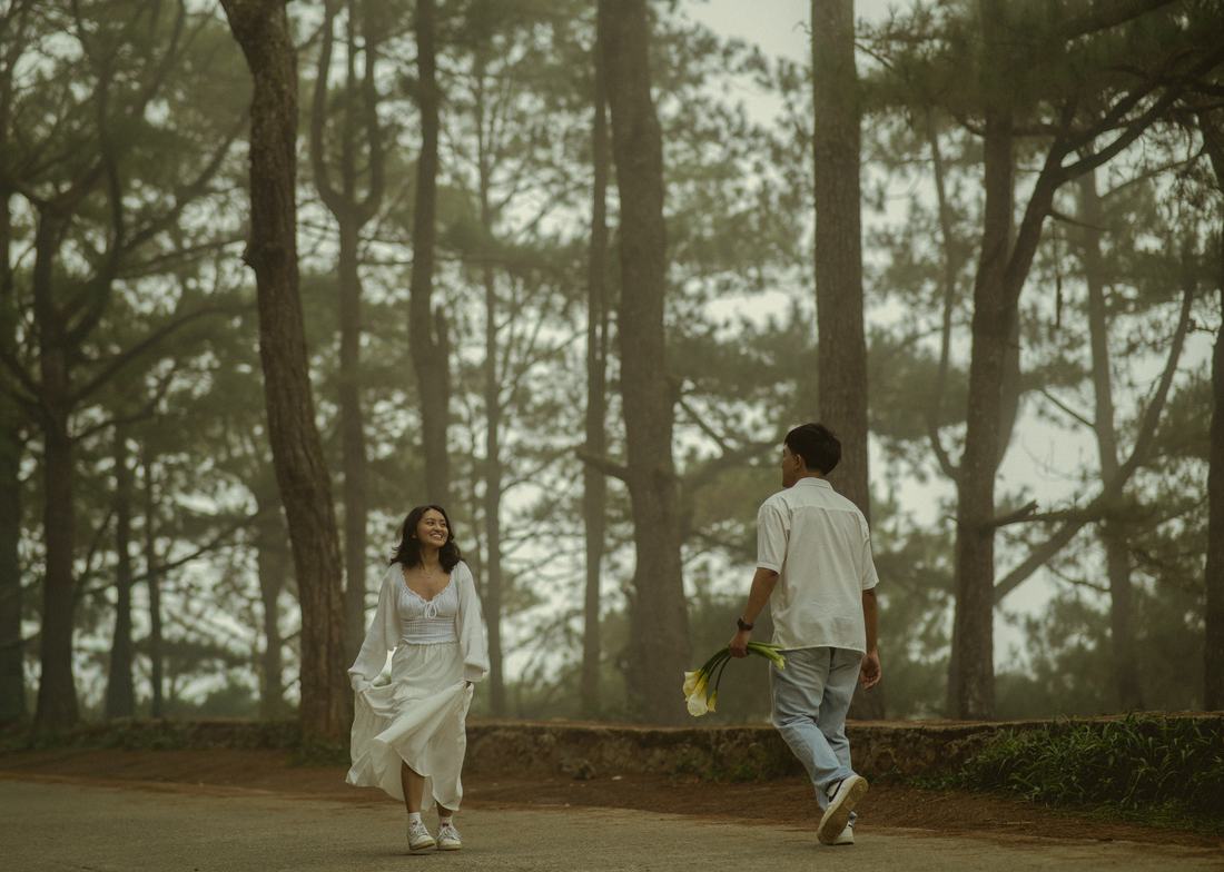 Bryan and Irey walking toward one another along a pine-lined road.